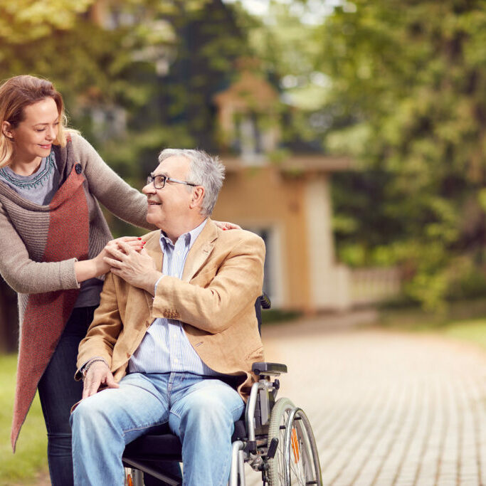 senior man in wheelchair with happy caregiver daughter